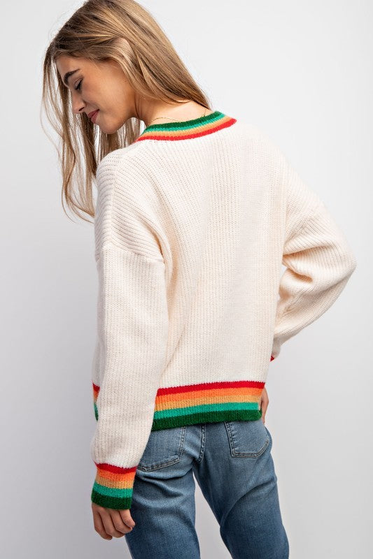 Woman wearing a cream sweater with rainbow stripes on a white background