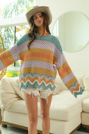 Woman wearing oversized crochet sweater with multicolor wavy stripes and open-knit design.