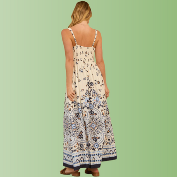 Back view of person wearing a cream maxi dress with blue floral border print and thin shoulder straps.