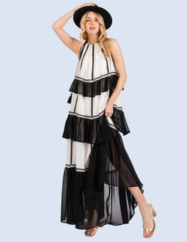 Woman wearing black and white color block maxi dress with tiered ruffles and embroidered details.