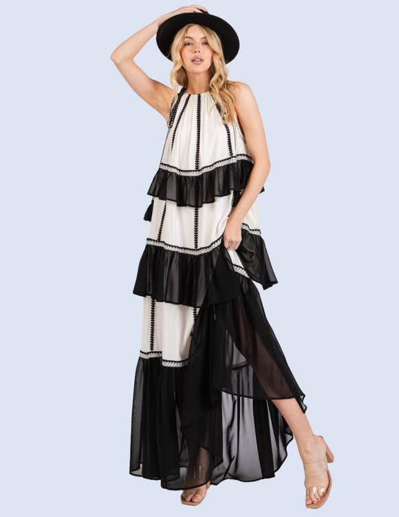 Woman wearing black and white color block maxi dress with tiered ruffles and embroidered details.