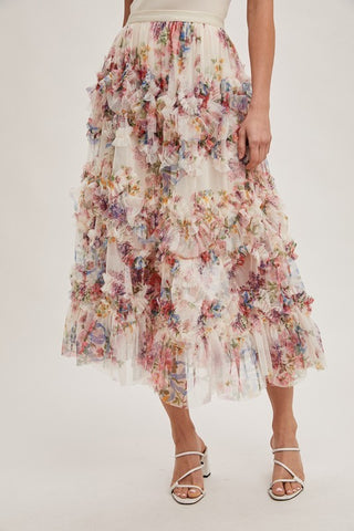 Woman wearing floral ruffled mesh midi skirt with tiered layers, soft lining, and flowy feminine silhouette.