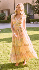 Person standing on grass wearing a pastel paisley print maxi dress with lace-trim V-neckline, cap sleeves, and a defined waist.