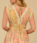 Back view of person wearing a pastel paisley print maxi dress with lace-trim V-back, smocked waist, and tie-back neck detail.