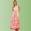 Front view of person wearing a cream maxi dress with red floral border print, straight neckline, and flowy maxi skirt.