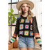 A female model wearing a multicolor crochet sweater with long sleeves, paired with denim shorts and accessorized with a hat and a watch.