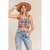 A female model wearing a multicolor crochet crop tank top with spaghetti straps and denim jeans, accessorized with a brown hat and a pink watch.