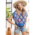 A woman wearing a multi-color crochet vest top with short sleeves, paired with denim shorts and a wide-brimmed hat.