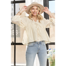 A woman wearing a beige long sleeve knit peasant blouse with puff sleeves, paired with blue jeans and a wide-brimmed hat.