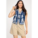 A female model wearing a blue denim vest with white embroidered details and a collar, paired with beige shorts.