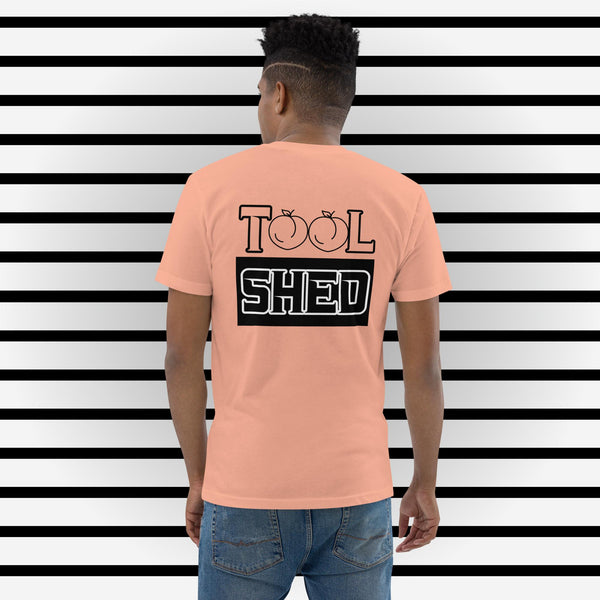 Peach Colored Short Sleeve T-Shirt. The word "TOOL" written across shoulders with the "O's" replaced with outline of peaches. The word sits on top of a black box with the word "SHED" done in a white outline written in the box.